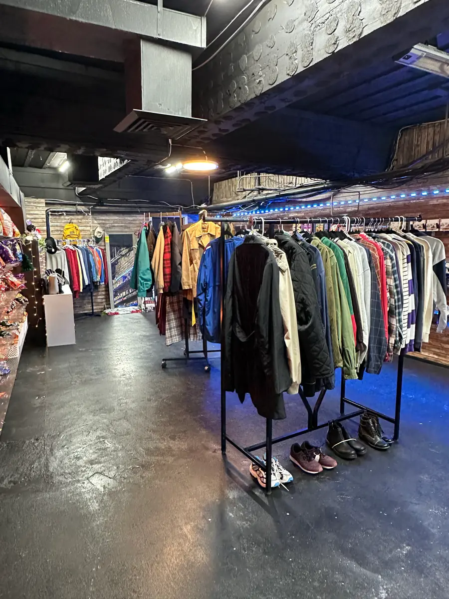 A full store floor with rows of jacket racks and shoes under blue accent lighting
