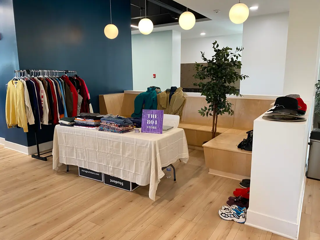 A pop-up setup: a draped table of folded shirts, two clothing racks, and a small The804Store sign