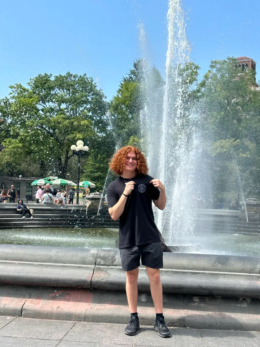 Isaiah standing in front of the Washington Square Park fountain in New York