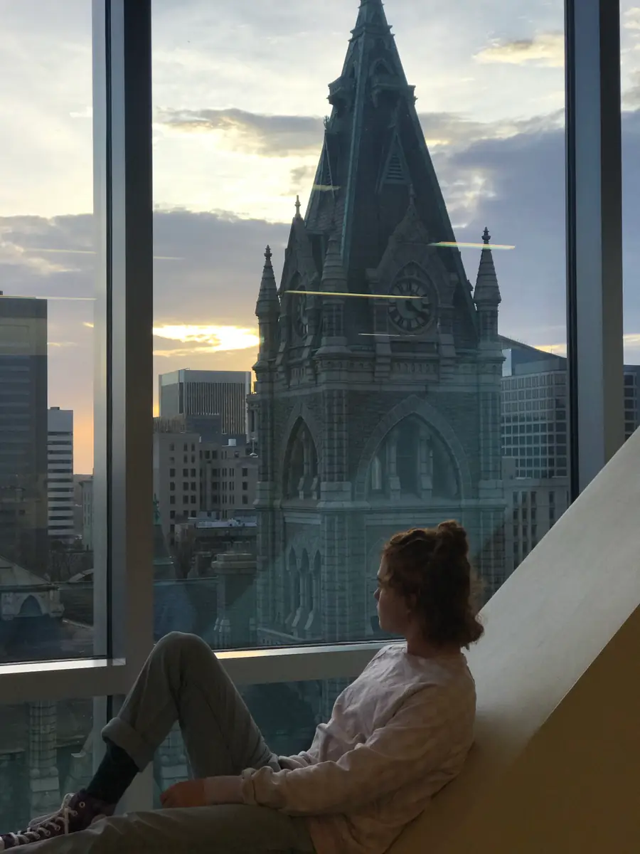 Isaiah sitting in a high window at sunset, looking out at Richmond's Old City Hall clock tower